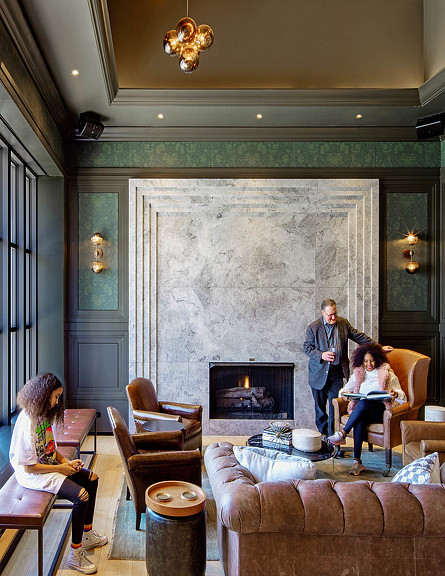A person standing in front of a fireplace with a couple of women sitting in chairs.